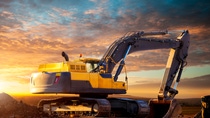 Excavator at a construction site against the setting sun. Excavator on the background of the setting sun. Huge excavator in the evening. Tracked excavator at the construction site in the evening.