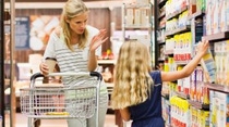 A woman with shopping cart and her daughter shopping at the supermarket