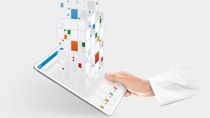 One hand protrudes from a white lab coat and holds a tray on which the LabAssitant KeyVisual can be seen One hand protrudes from a white lab coat and holds a tray on which the LabAssitant KeyVisual can be seen