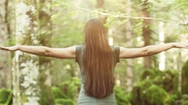 Woman spreading her arms in the forest back view: balance, spirituality and nature concept