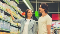 Beautiful young couple is talking and smiling while choosing food in the supermarket