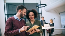 Coworkers standing in an office, looking at a digital tablet Coworkers standing in an office, looking at a digital tablet