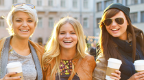 Women look into the camera and hold sustainable coffee packaging in their hands.
