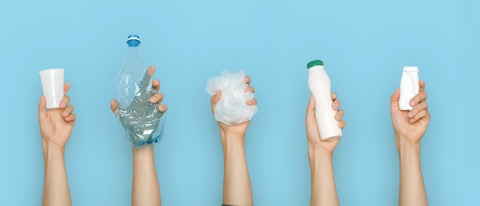 Concept of garbage sorting and ecology. Photo for website banner. Hands holding different trash on a blue background.