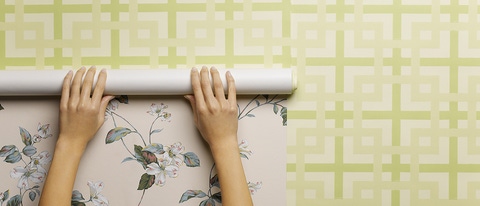 Woman wallpapering wall, close-up